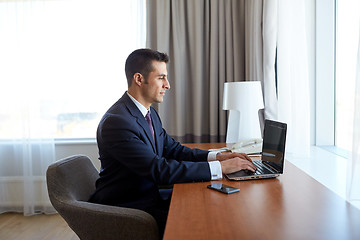 Image showing businessman typing on laptop at hotel room
