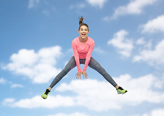 Image showing happy smiling sporty young woman jumping in sky