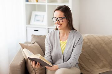 Image showing young woman in glasses reading book at home