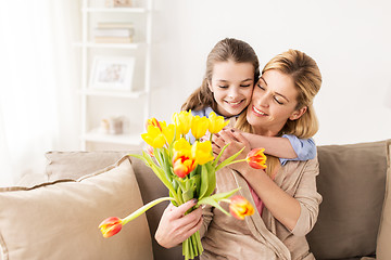 Image showing happy girl giving flowers to mother at home