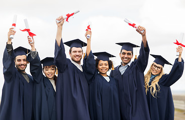 Image showing happy students in mortar boards with diplomas