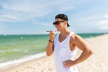 Image showing smiling man calling on smartphone on summer beach