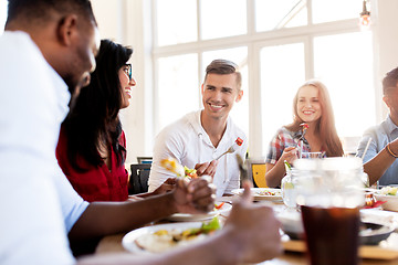 Image showing happy friends eating and talking at restaurant