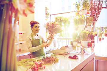 Image showing smiling florist woman making bunch at flower shop