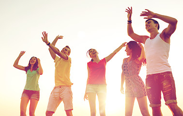 Image showing smiling friends dancing on summer beach