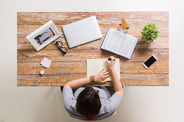 Image showing woman with book writing to notebook at table