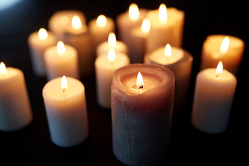 Image showing candles burning in darkness over black background