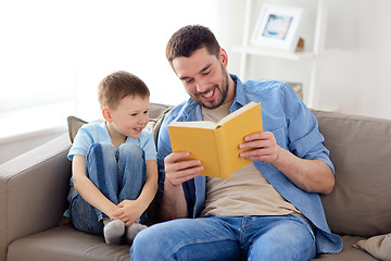 Image showing happy father and son reading book sofa at home