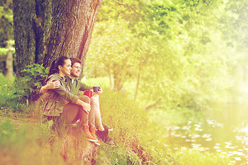 Image showing happy couple with cups drinking tea in nature