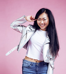 Image showing young pretty smiling asian korean girl wearing modern fashion clothers on pink background, lifestyle people concept 