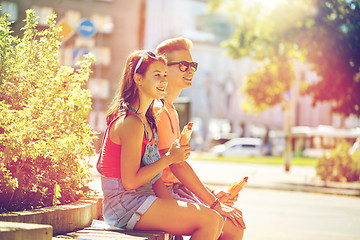 Image showing happy teenage couple eating hot dogs in city