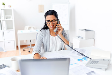 Image showing businesswoman calling on desk phone at office