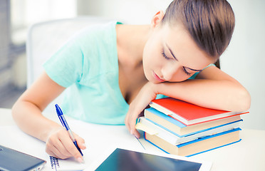 Image showing tired student sleeping on stock of books