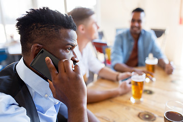 Image showing man calling on smartphone and drinking beer at bar