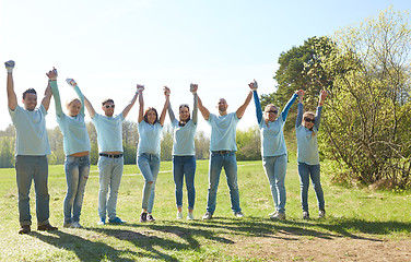 Image showing group of happy volunteers holding hands outdoors