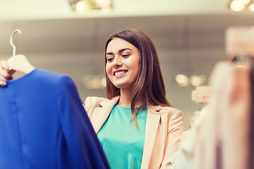 Image showing happy young woman choosing clothes in mall