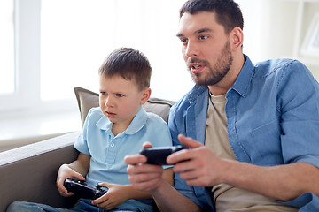 Image showing father and son playing video game at home