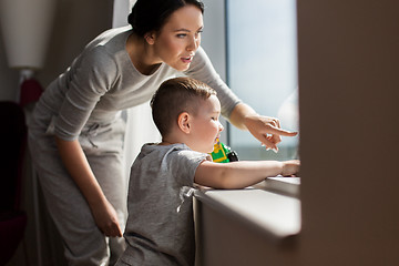 Image showing mother and son looking through window at home