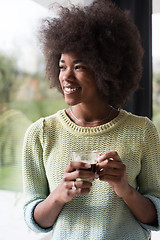 Image showing African American woman drinking coffee looking out the window