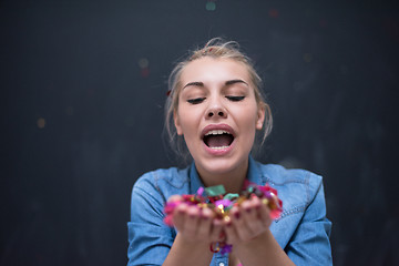 Image showing woman blowing confetti in the air