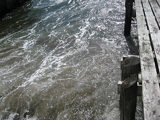 Image showing Stirred up water against a old wooden dock