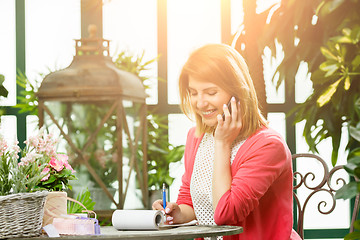 Image showing Florist on phone takes orders