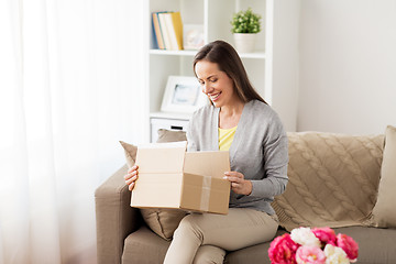 Image showing smiling woman opening cardboard box