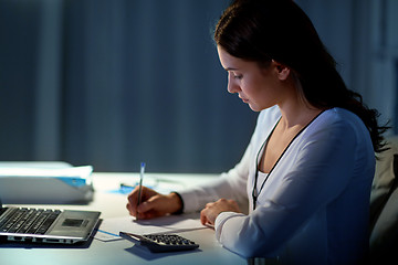 Image showing woman with calculator and papers at night office