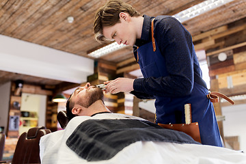 Image showing man and barber with trimmer cutting beard at salon