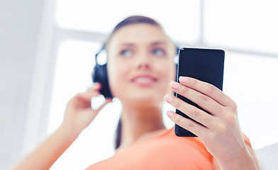 Image showing woman with headphones and smartphone at home