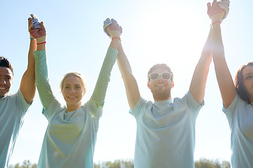 Image showing group of happy volunteers holding hands outdoors