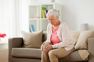 Image showing senior woman suffering from pain in leg at home