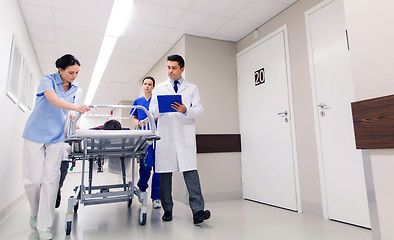 Image showing medics with woman on hospital gurney at emergency