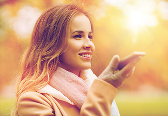 Image showing woman recording voice on smartphone in autumn park