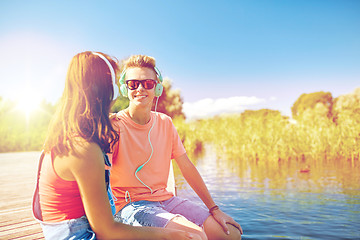 Image showing happy teenage couple with earphones on river berth