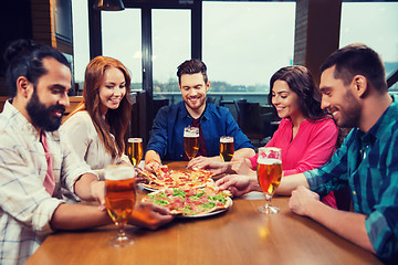 Image showing friends eating pizza with beer at restaurant