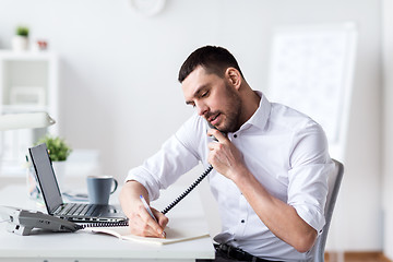 Image showing businessman with pad calling on phone at office