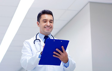 Image showing smiling doctor with clipboard at hospital corridor