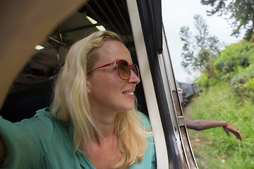 Image showing Blonde caucasian woman riding a train, looking trough window.