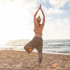 Image showing Woman practicing yoga on sea beach at sunset.