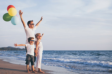 Image showing Father and children with balloons playing on the beach at the da