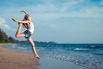 Image showing One teen girl  jumping on the beach at the day time. 