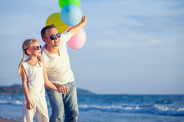 Image showing Father and daughter with balloons playing on the beach at the da