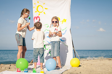 Image showing Two sisters and brother playing on the beach at the day time.