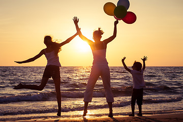 Image showing Mother and children playing with balloons on the beach at the su