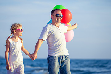 Image showing Father and daughter with balloons playing on the beach at the da