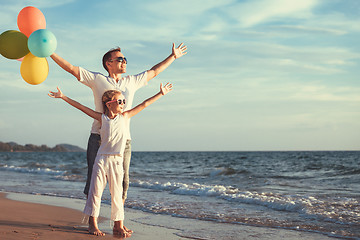 Image showing Father and daughter with balloons playing on the beach at the da