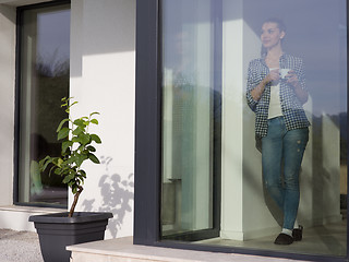 Image showing young woman drinking morning coffee by the window