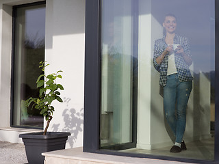 Image showing young woman drinking morning coffee by the window