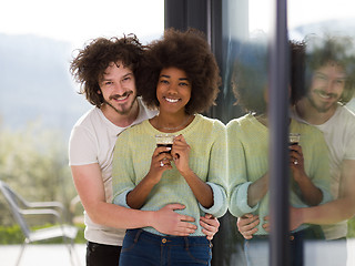 Image showing happy multiethnic couple relaxing at modern home indoors